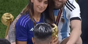 Lionel Messi abrazando a su esposa Antonela Roccuzzo mientras sostiene el trofeo de la Copa del Mundo 2022, celebrando en el campo tras la victoria de Argentina.